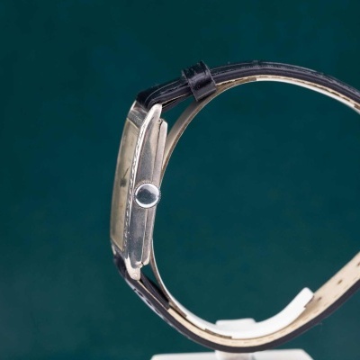 Relógio de pulso com caixa retangular prateada e bracelete preta de couro