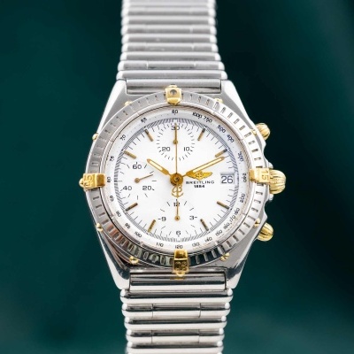 Relógio Breitling metálico com mostrador branco e detalhes dourados