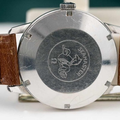 Relógio com bracelete de couro castanho e parte traseira metálica gravada com texto