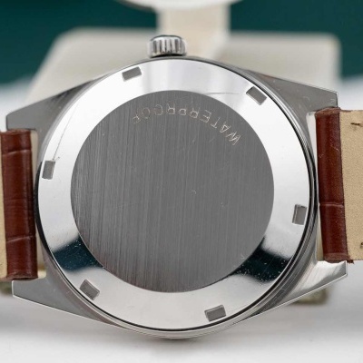 Relógio com caixa metálica e pulseira de couro bege e castanho