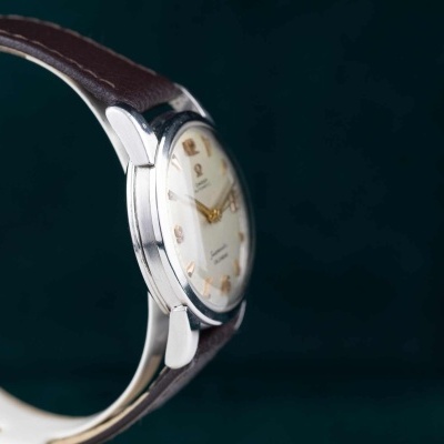 Relógio de pulso metálico com correia de couro castanho e mostrador branco