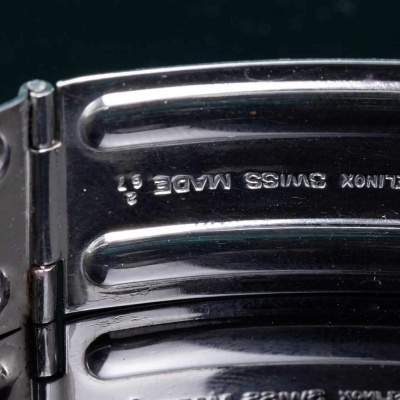 Bracelete metálico prateado com gravação interna e fundo escuro