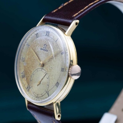 Relógio de pulso vintage Omega com mostrador dourado e pulseira castanha