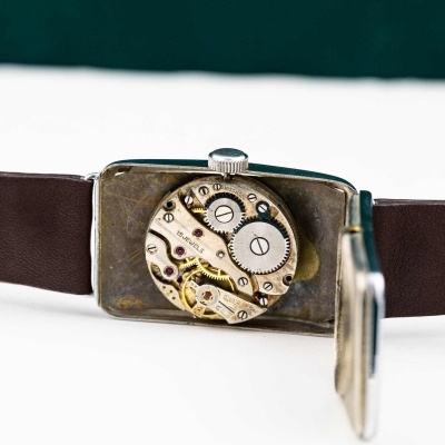 Relógio de pulso com mecanismo interno visível e bracelete em couro castanho.