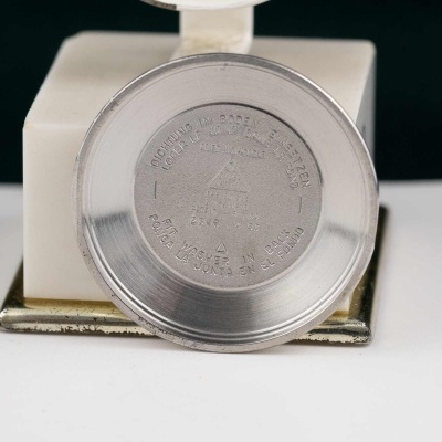 Parte inferior de relógio com tampa metálica e texto gravado