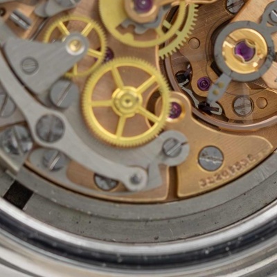 Mecanismo interno de relógio com engrenagens douradas e partes metálicas cinza