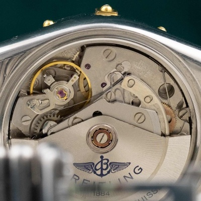 Mecanismo interno de relógio Breitling com texto e metais prateados e dourados