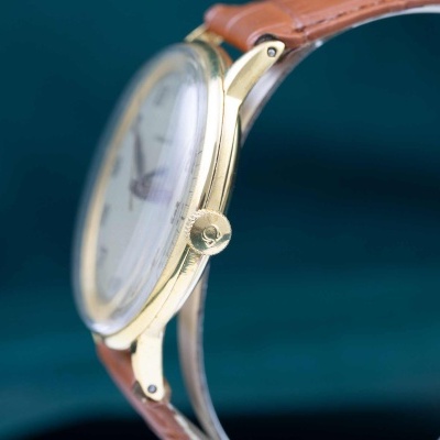 Relógio de pulso com caixa dourada e correia castanha em couro