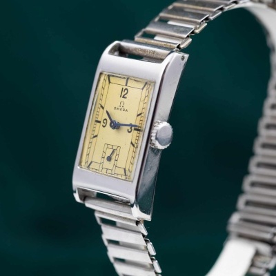 Relógio de pulso Omega retangular em aço com mostrador amarelo.