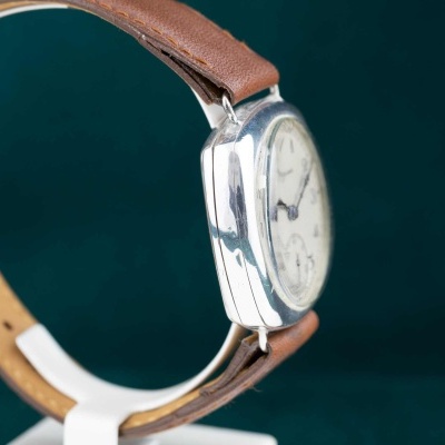 Relógio de pulso com bracelete castanha e caixa prateada visto de lado