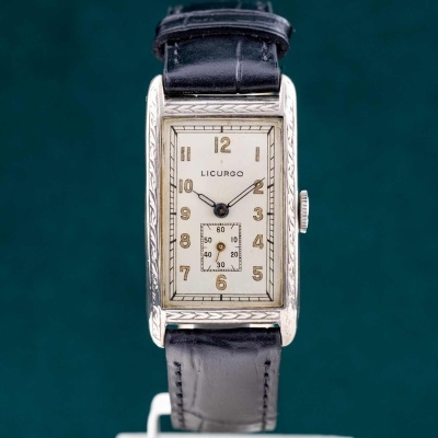 Relógio de pulso retangular com bracelete preta e mostrador creme com números dourados