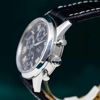 Relógio masculino de aço com bracelete preta em pele e mostrador preto com números romanos amarelos.