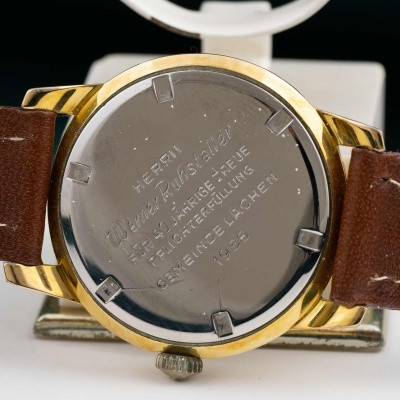 Relógio com caixa dourada, traseira em aço inoxidável gravada e bracelete de pele castanha