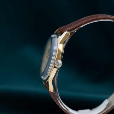 Relógio dourado com bracelete castanha de couro e vidro convexo