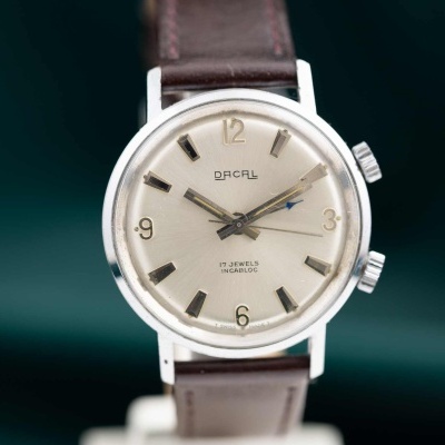 Relógio de pulso Dacal com mostrador prata e pulseira castanha de couro.