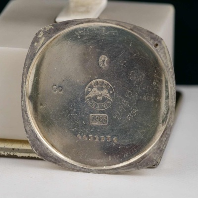 Parte traseira de caixa de relógio prateada com marca e números gravados