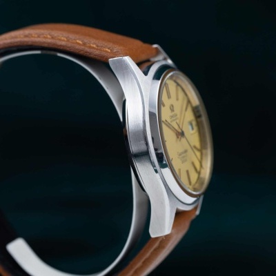 Relógio de pulso com caixa prateada, mostrador amarelo e bracelete castanha de couro