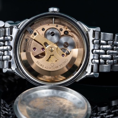 Relógio mecânico com mecanismo interno visível e bracelete metálica prateada