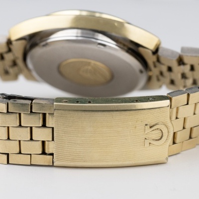 Relógio de pulso metálico com bracelete dourada e fecho com símbolo