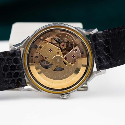 Relógio com bracelete preta em couro e mostrador transparente que mostra o mecanismo interno