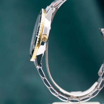 Relógio de pulso metálico com bracelete prateada e moldura dourada e preta