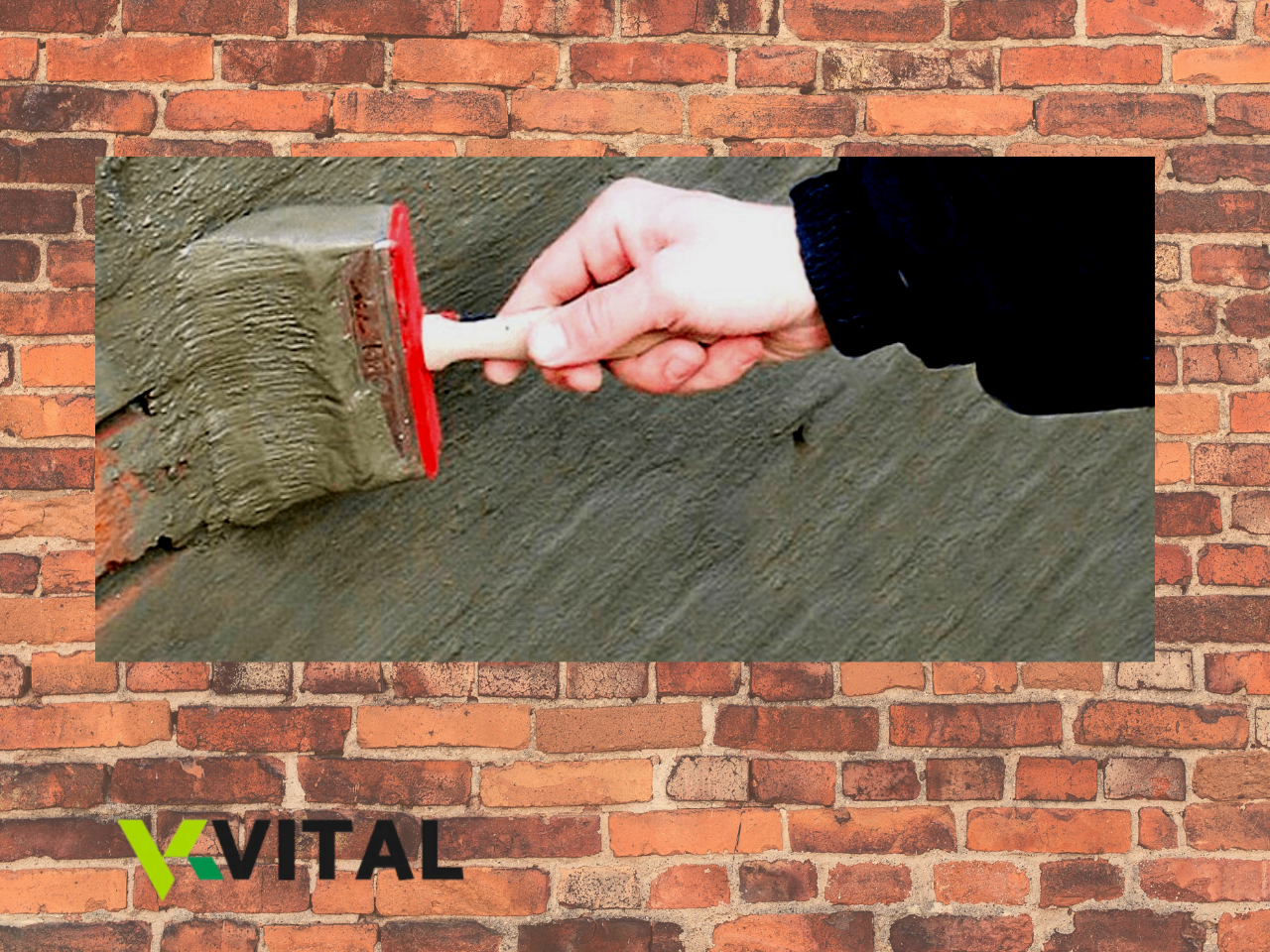 Mão a aplicar argamassa cinzenta numa parede com espátula vermelha e branca, logótipo VITAL no canto