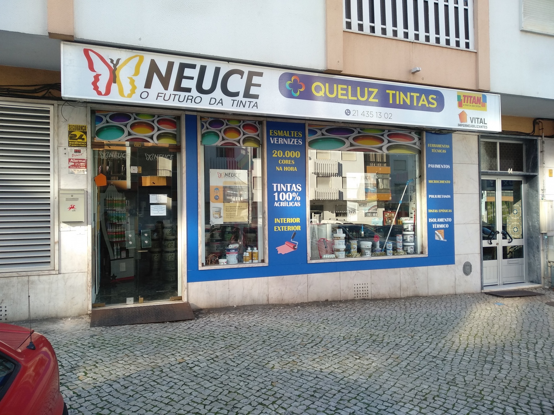 Fachada de loja de tintas com letreiros e vitrines mostrando baldes de tinta