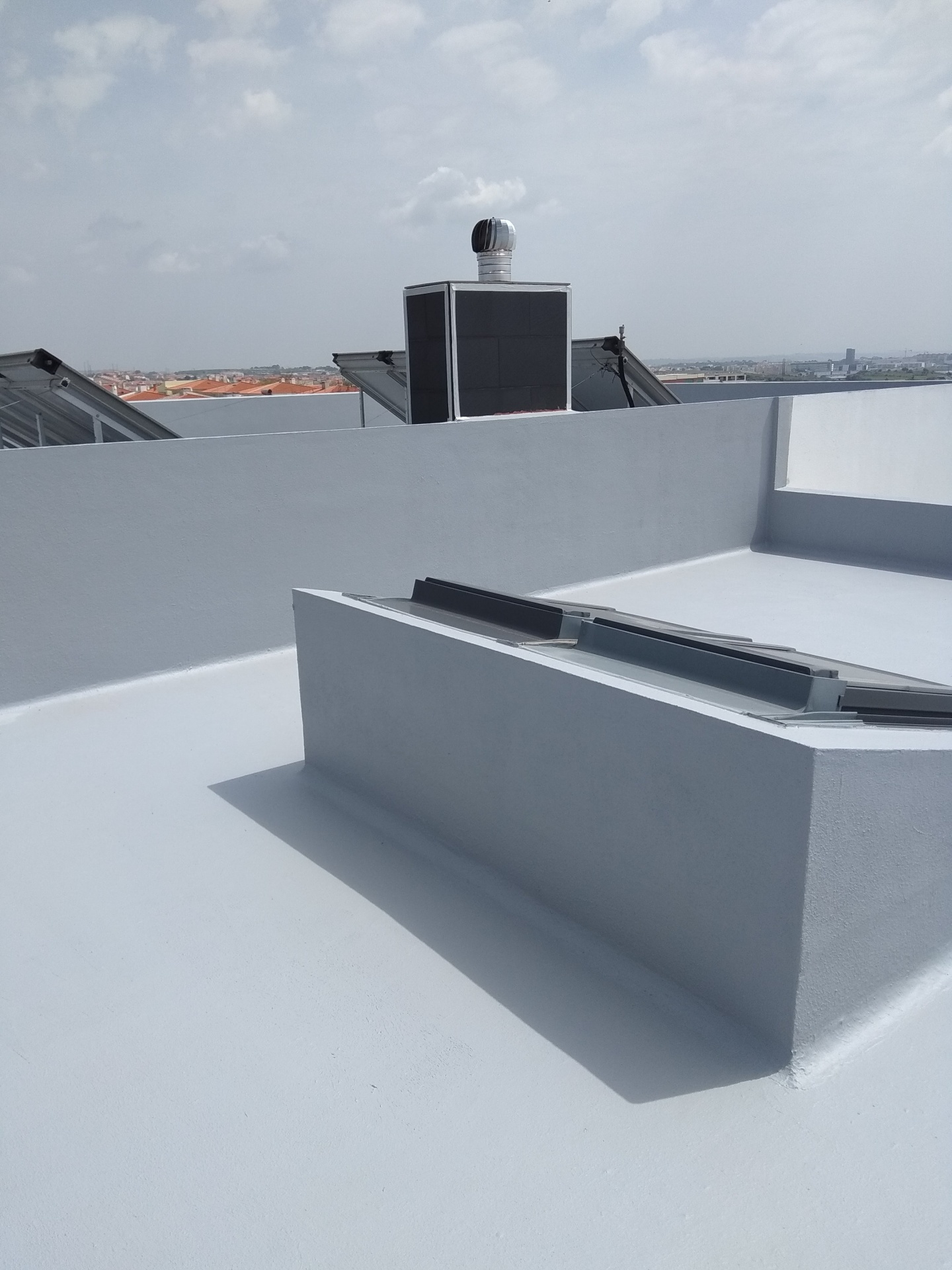 Terraço com piso e paredes cinzentas e estruturas metálicas