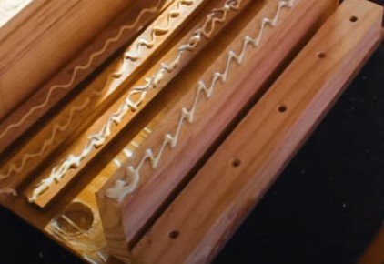 Molduras de madeira com cola branca em padrão ziguezague sobre superfície preta