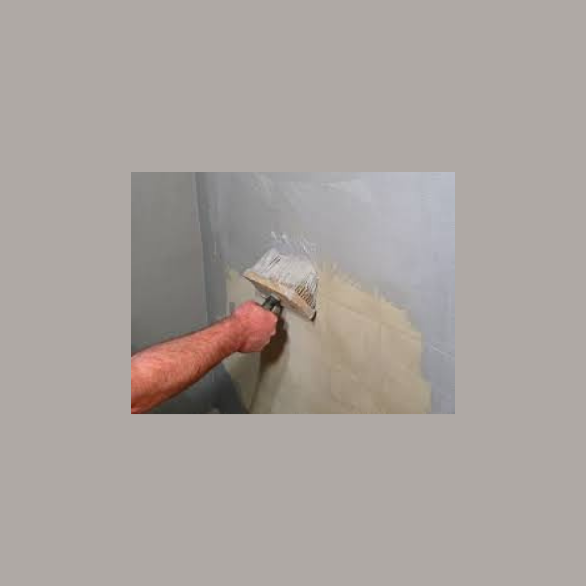 Pessoa a aplicar revestimento numa parede cinzenta com desempenadeira.