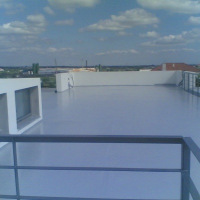 Terraço amplo com piso branco, guarda-corpos cinzentos e vista para edifícios e céu azul