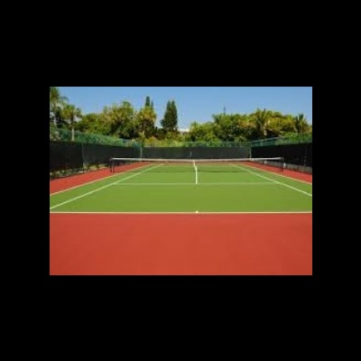 Campo de ténis ao ar livre com piso verde e vermelho cercado por rede preta e árvores ao fundo