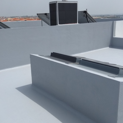 Telhado plano branco com aparelhos solares cinza escuro e vista urbana ao fundo