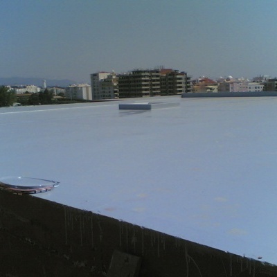 Telhado plano branco com estruturas circulares e edifícios ao fundo