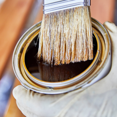 Pincel com cerdas claras a mergulhar na tinta castanha numa lata metálica aberta