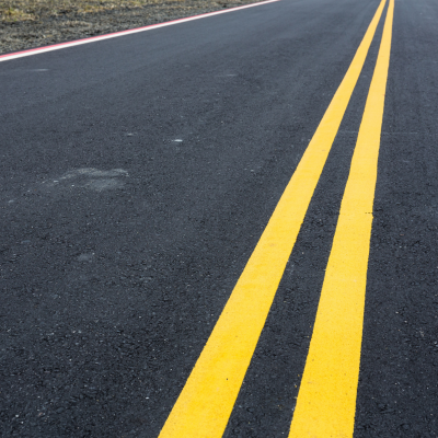 Troço de estrada asfaltada com linhas amarelas contínuas ao centro