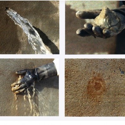 Mão com luva preta segurando areia molhada e água a escorrer na praia