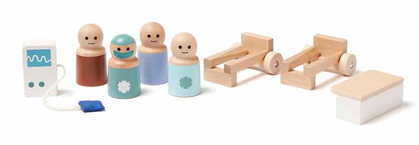 Brinquedos de madeira representando figuras humanas, camas, mesa e monitor médico