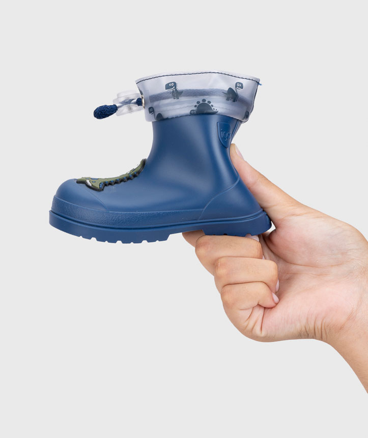 Bota infantil azul com punho cinzento e cordão azul segurada por mão