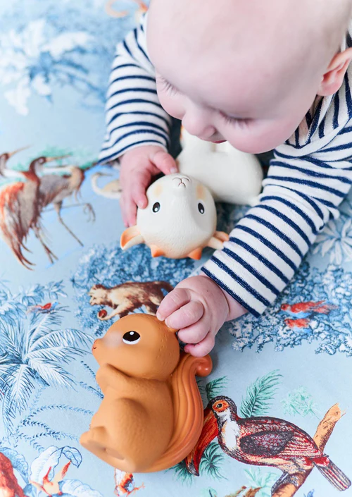 Bebé a brincar com brinquedos de esquilo sobre tecido estampado azul