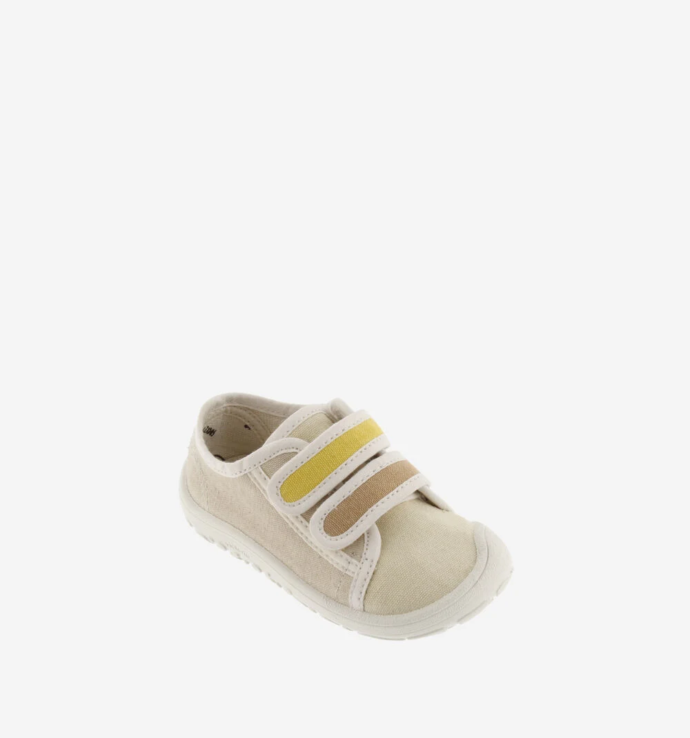 Tênis infantil em tecido bege claro com sola branca e fechos de velcro amarelo e castanho