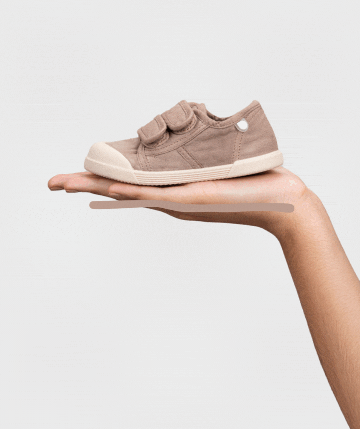 Ténis infantil bege com fecho de velcro numa mão