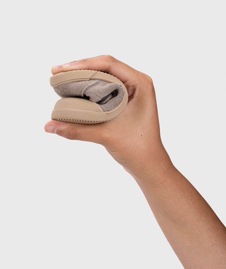 Mão a segurar sandália dobrada bege flexível