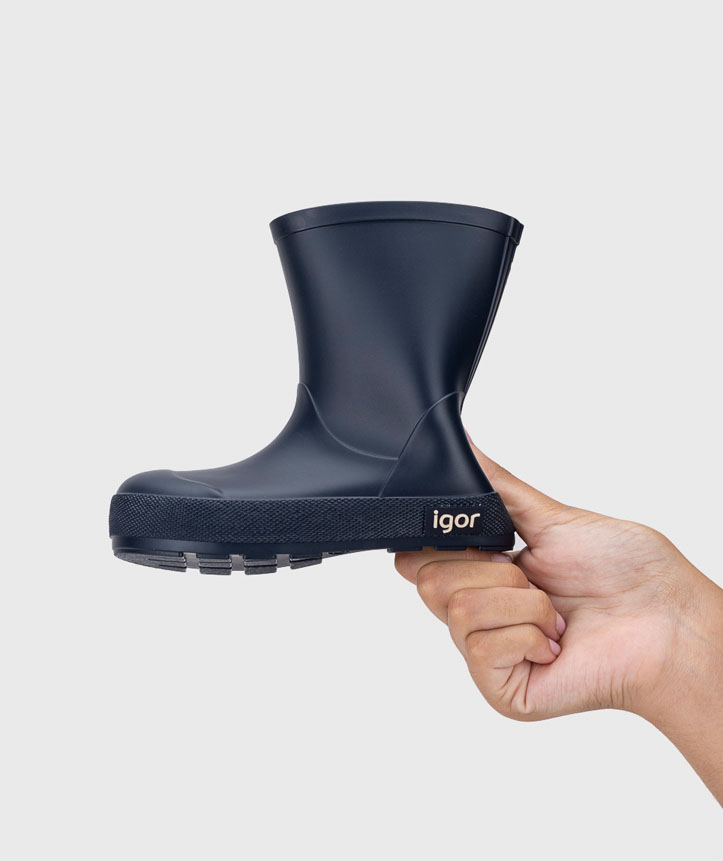Bota impermeável azul escura Igor para criança segurada por uma mão