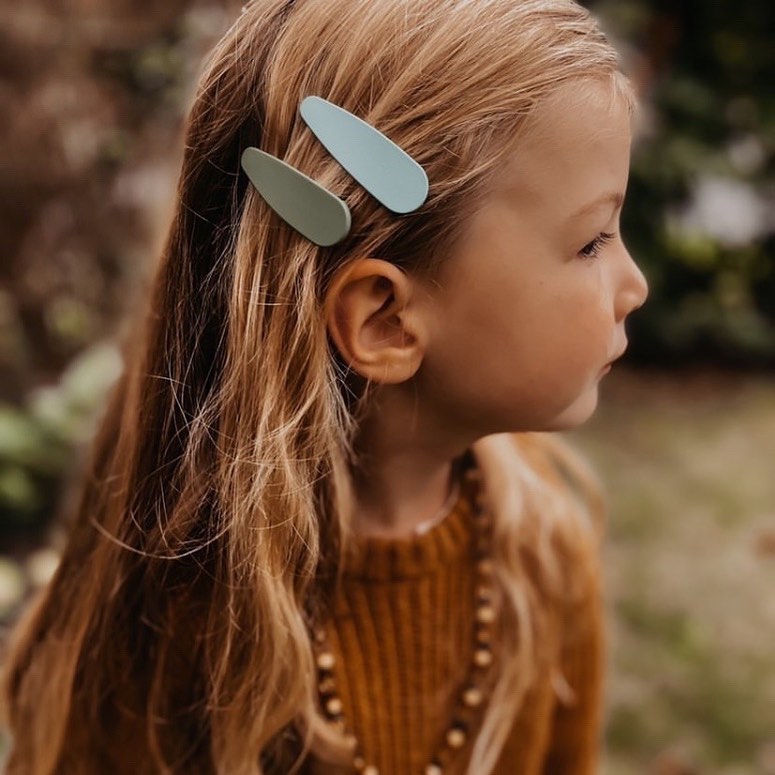 Clipe de cabelo azul claro e verde em cabelo loiro de criança