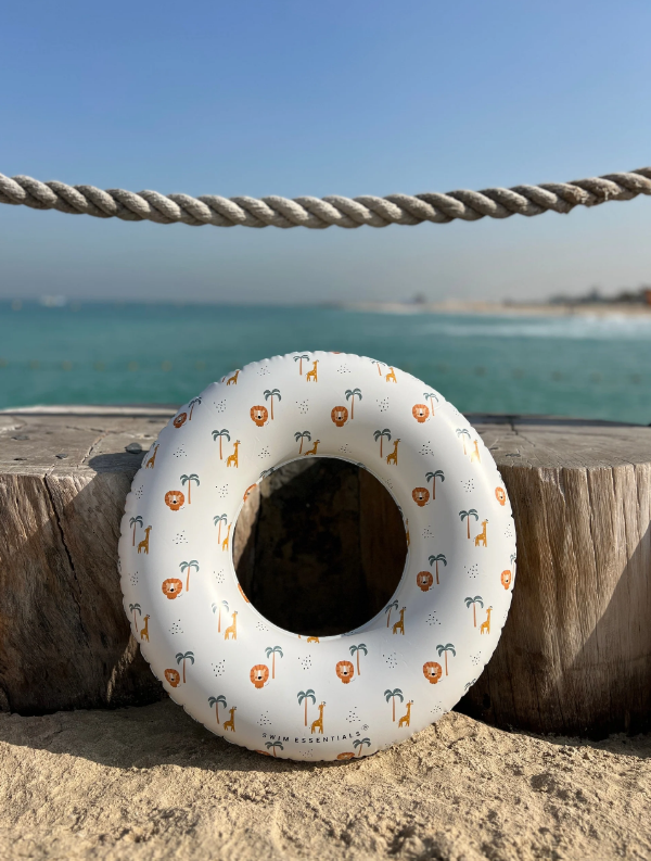 Boia insuflável branca com desenhos de leões, girafas e palmeiras junto à praia