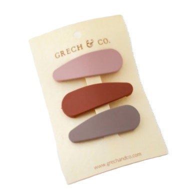 Três molas de cabelo em diferentes tons montadas em cartão creme com logotipo