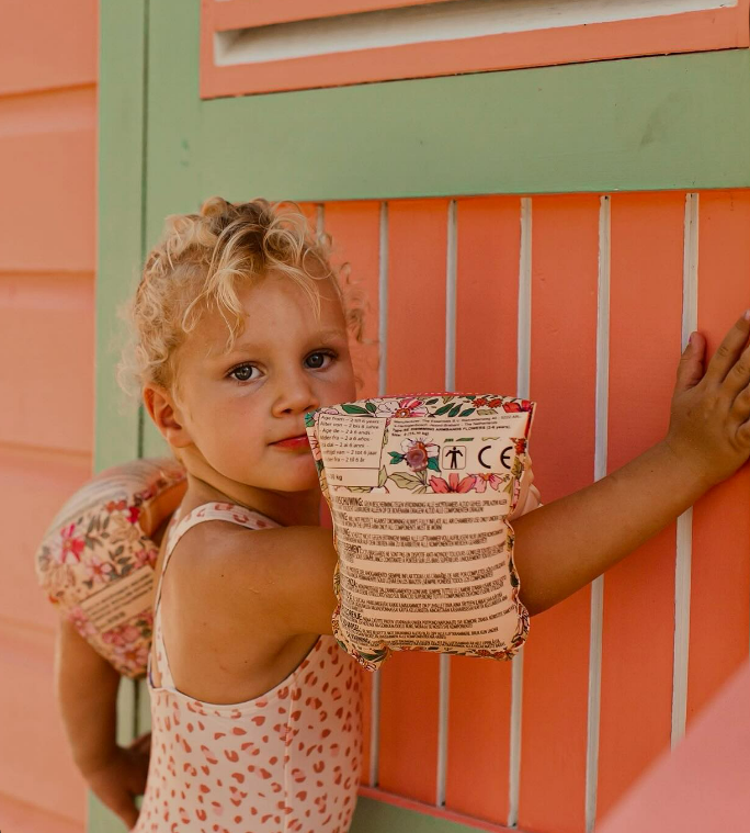 Menina com colete salva-vidas inflável junto a parede colorida