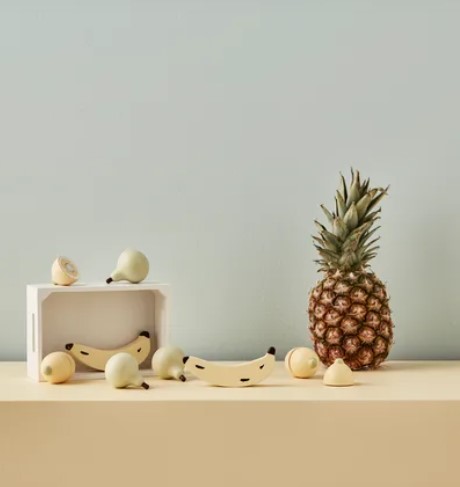 Ananás, micróbios brancos e réplicas de bananas sobre superfície bege