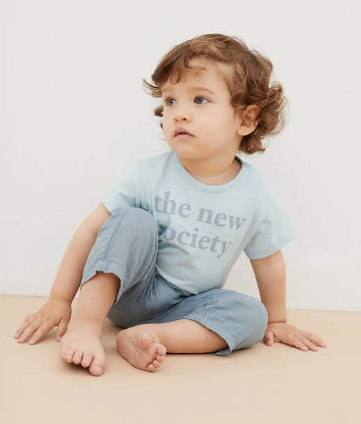 Criança sentada no chão com t-shirt azul clara e calças azuis